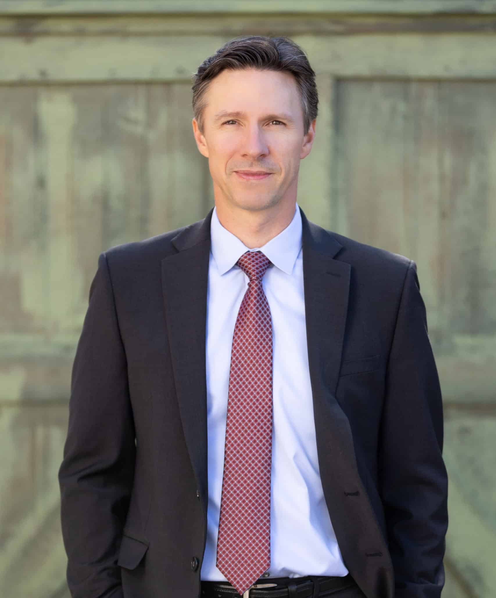 A headshot of Bill standing in front of a green door